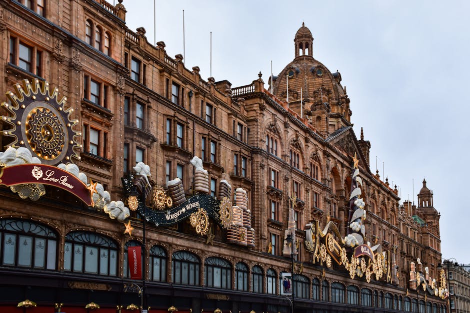 An ornate historical building with intricate architectural details, including large arched windows and decorative stonework, decorated with festive Christmas ornaments such as gingerbread house decorations, stars, and cotton-like snowy accents. The building's facade is illuminated by warm lighting, highlighting its classical design and rich textures. Visible in the foreground are large, blue-tinted windows, with the overall scene suggesting a festive holiday display. The environment appears clean and well-maintained, consistent with professional deep cleaning and sanitisation standards. Relevant to residential and commercial cleaning services provided by Cleaners Knightsbridge for maintaining high hygiene and aesthetic standards in prominent, busy locations like Knightsbridge.